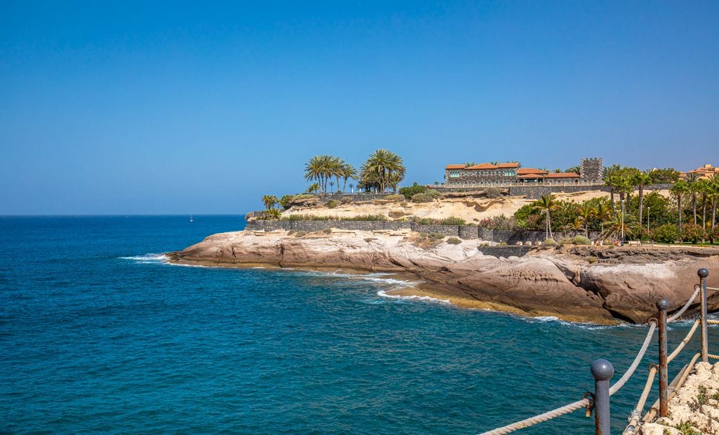 Beautiful coastal scenery at Costa Adeje, with clear blue waters and rocky cliffs under a sunny sky.
