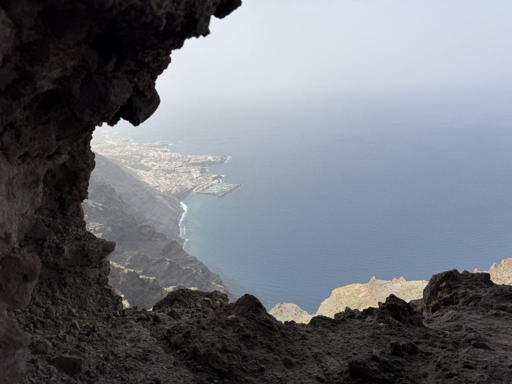 Vue à travers l'arche d'El Agujero sur la côte et le port en contrebas
