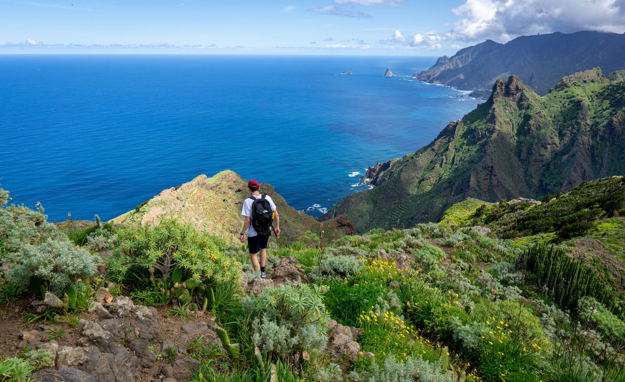 Randonneur avec sac à dos sur un sentier d'Anaga, vue sur la côte