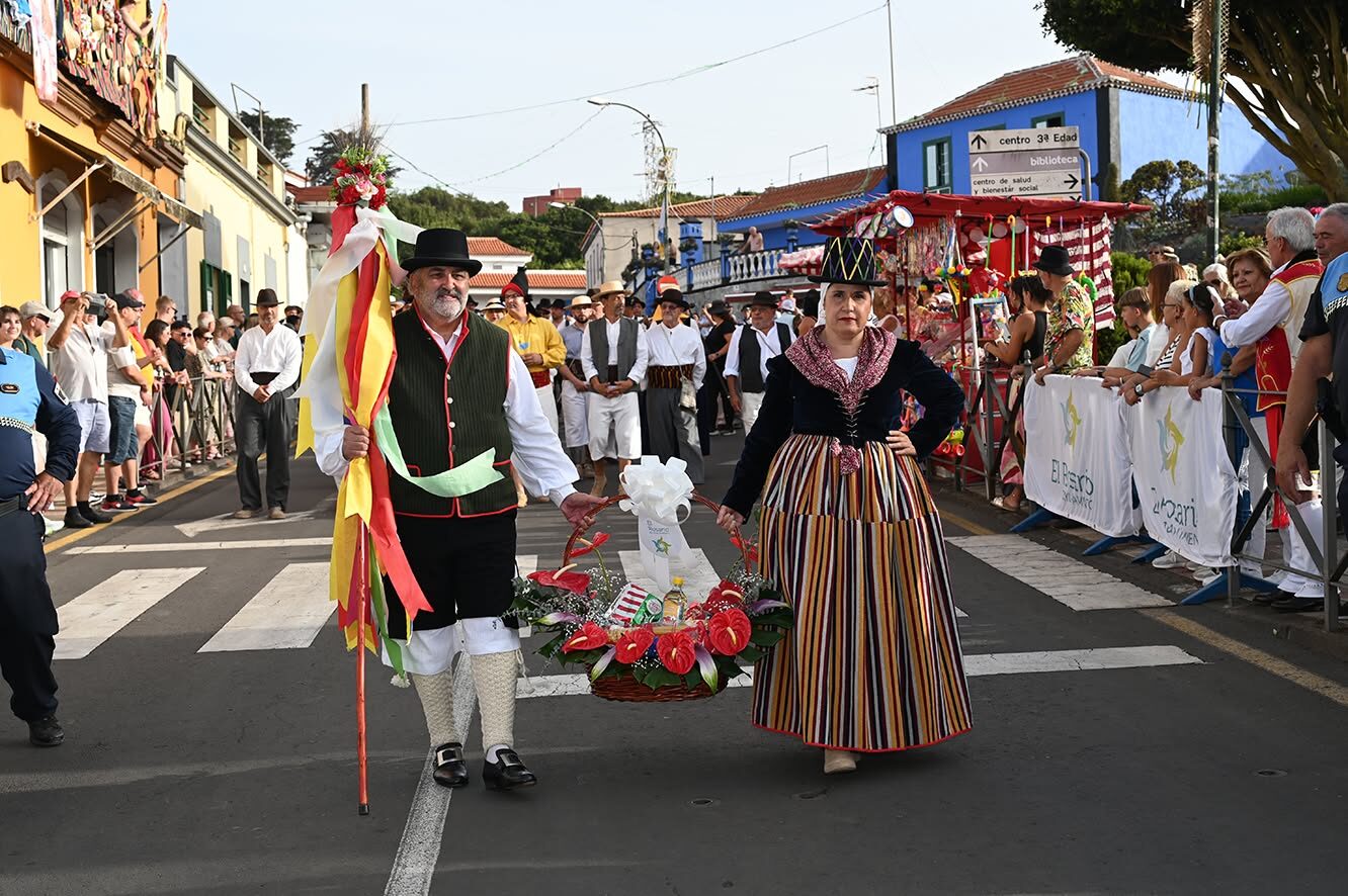 Couple en costume traditionnel canarien portant une offrande fleurie lors d'une romería